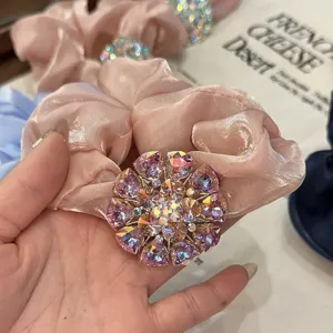Gros plan d'un chouchou en soie rose avec un centre scintillant en strass de cristal.