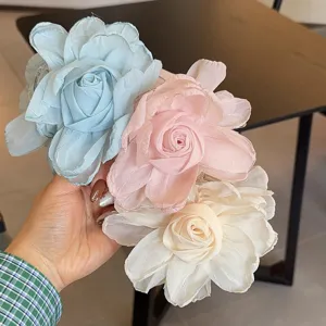 Gros plan de pinces à cheveux élégantes en tissu rose, bleu et blanc avec design floral.