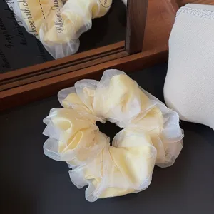Detailfoto van lichtgeel dubbellaags organza haarelastiekje, pluizig en zoet ontwerp.