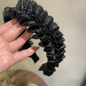Black pleated crystal headband detailed view, shiny fabric design for women hair styling.