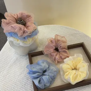 Gedetailleerde close-up van doorschijnende organza haarelastiekjes in zachte pastelkleuren.
