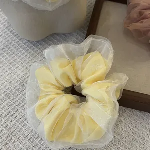 Gedetailleerd uitzicht van dubbellaags organza haarelastiek, zoete gele en witte haaraccessoire.
