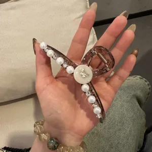 Nahaufnahme des eleganten Haargreifens aus Harz mit Perlen, Strass und niedlichem Schmetterling.