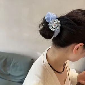 Chouchou en mousseline bleue chic avec fleur en strass étincelante pour coiffure élégante.