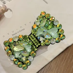 Close-up van strass strik haarspeld, sprankelende groene kristaldetails voor elegante look.