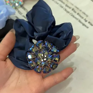 Gros plan détail du chouchou en satin bleu foncé avec des cristaux de fleurs en strass étincelants.