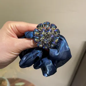 Chouchou de cheveux en satin bleu fonce elegant avec accessoire de fleur en strass scintillant.