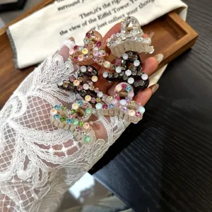 Primer plano detallado de mini pinzas para el cabello brillantes con strass en la mano.
