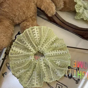 Nahaufnahme Detail des hellgrünen Spitzen-Haargummis, süßes Netz-Rüschen-Haaraccessoire.