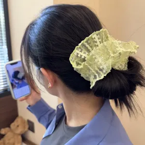 Nahaufnahme des hellgrünen Spitzen Haargummis, elegantes Haaraccessoire für tägliches Styling.