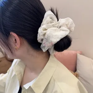 Nahaufnahme des weißen Spitzen Haargummis mit Blumenmuster, süßes Haaraccessoire.