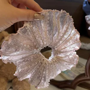 Detailansicht des rosa spitzen-Haargummis mit feinen Rüschen und klarer Textur.