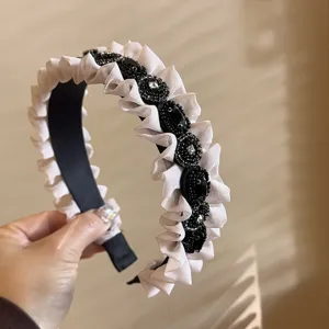 Close-up detail of stylish ruffled rhinestone headband with black beaded embellishments.