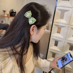 Gedetailleerd overzicht van de sprankelende groene strass strik haarspeld, luxe design.