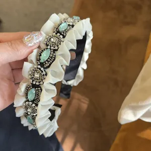 Close-up detail of vintage ruffled rhinestone headband with elegant sparkling crystal stones.