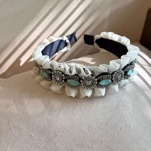 Elegant vintage rhinestone headband with white ruffled edge and sparkling blue crystal stones.