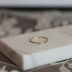 Gros plan detaille sur une bague minimaliste plaque or 14k avec pierre etincelante