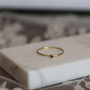 Bague minimaliste en argent sterling plaqué or 14k avec une fine pierre rouge sertie.