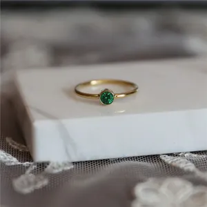Gros plan détaillé d'une bague minimaliste en argent plaqué or 14k avec pierre verte.
