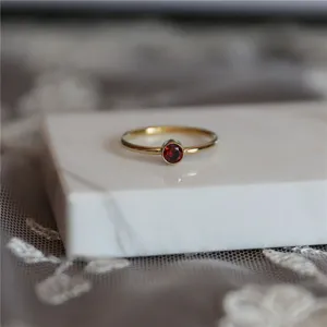 Gros plan détaillé d'une bague minimaliste avec pierre rouge et argent plaqué or 14K.