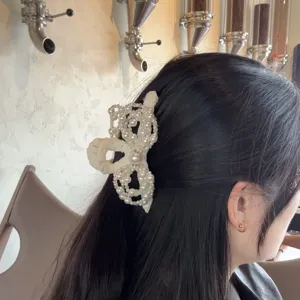 Detailaufnahme der eleganten Perlen Schleife Haarklammer am dunklen Kopfhaar getragen.