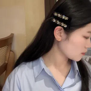 Détail de pince à cheveux en velours strass avec cristaux étincelants sur clip noir.