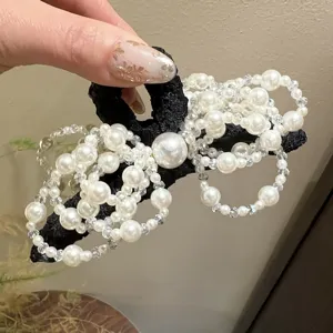 Perlen Schleife Haarklammer Detail, elegante schwarze Basis mit glänzenden Perlen ideal.