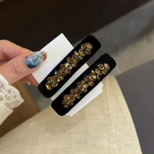 Vue détaillée de la pince en velours noir coréen ornée de cristaux champagne scintillants.