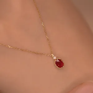 Nahaufnahme der filigranen goldenen Kette mit einem eleganten roten Rubin Anhänger glänzt.