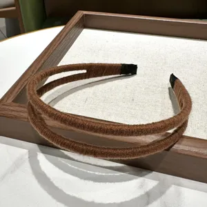 Nahaufnahme des braunen Woll-Haarbandes im Doppelstrang-Design, minimalistisch und retro.