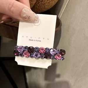 Gros plan de detail de barrette a cheveux strass scintillante avec cristaux colores sur carte blanche.