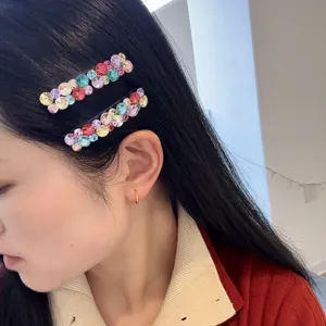 Gros plan détaillé des pinces à cheveux en strass colorés portées sur le côté, style élégant.