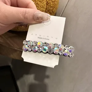 Détail de la barrette à cheveux en strass avec des cristaux colorés sur un support blanc.