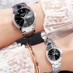 Vue rapprochée de détail de montres à quartz pour couple avec cadran noir et bracelet en acier.