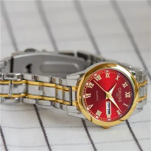 Gros plan sur les details de la montre pour femme au cadran rouge et bracelet bicolore.