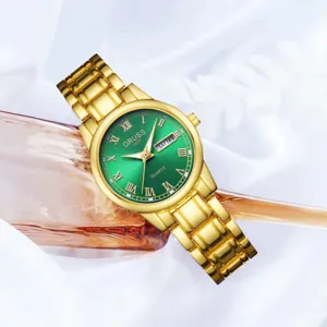 Élégante montre quartz pour femme avec cadran vert et bracelet en métal doré.
