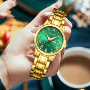 Vue détail montre quartz femme cadran vert bracelet métal doré et affichage du calendrier.