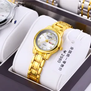 Golden quartz women's watch with white dial roman numerals and metal link strap luxury style.