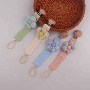 Detailed close-up of cute handmade fabric flower pacifier clips with natural wooden beads.