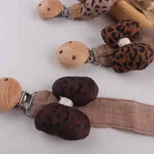 Détail de l'attache-tétine imprimé léopard, tissu doux et perles en bois naturel.