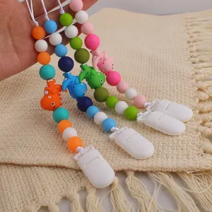 Silicone pacifier clip detail featuring colorful dinosaur beads and secure white holder.