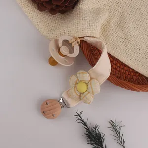 Detailed close-up of a baby pacifier clip featuring a fabric flower and wooden clip design.