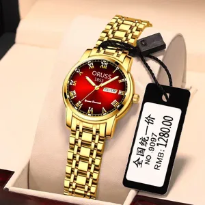 Detalle de primer plano del elegante reloj de cuarzo dorado con esfera roja brillante.