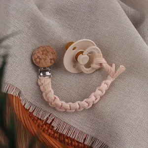 Detailed shot of the baby pacifier clip with braided cotton cord and wooden flower clip.