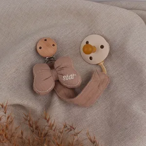 Detail view of baby pacifier clip and dummy set with cute bow and star embroidery.