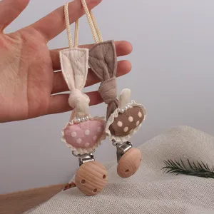 Close-up detail of cute mushroom fabric pacifier chain with wooden clip and pearl decor.
