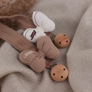 Detail shot of baby pacifier clip with fabric bow and wooden button, soft texture and safe.