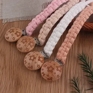 Handmade woven macrame baby pacifier clip featuring natural wooden floral clip detail.