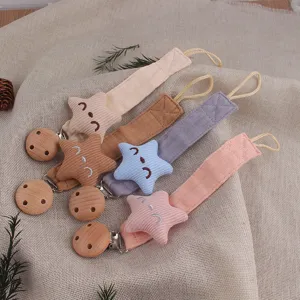 Close up of cute baby pacifier clips with colorful fabric smiling star and wooden clip.