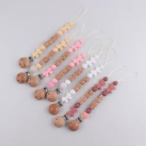 Silicone wooden baby pacifier clip teething toy set with cute bows and beads for infants.